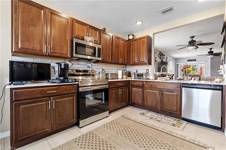 Kitchen with appliances with stainless steel finishes, ceiling fan, backsplash, light tile patterned flooring, and recessed lighting