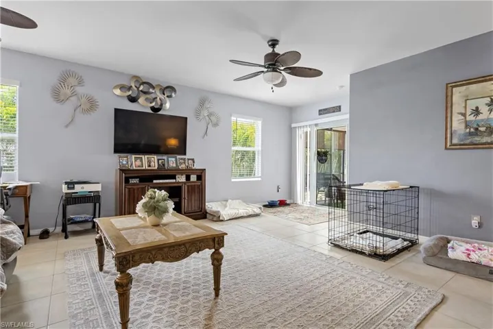 Living area featuring ceiling fan, light tile patterned floors, and baseboards