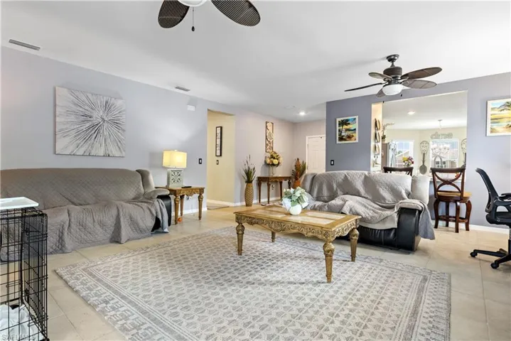 Tiled living room with ceiling fan and baseboards