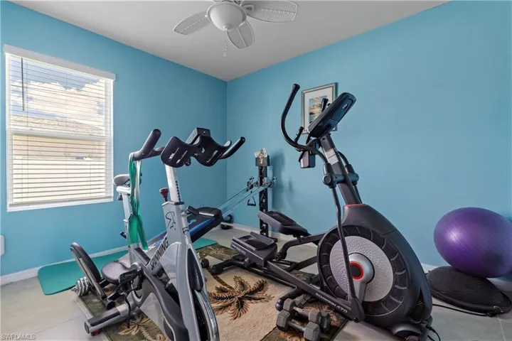 Exercise room with a ceiling fan and baseboards