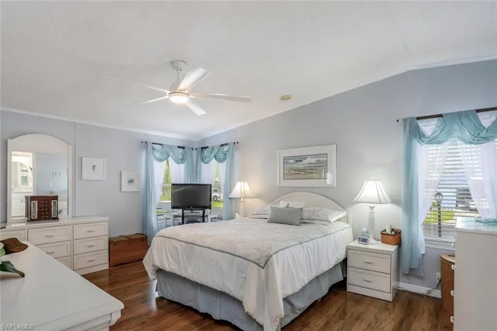 Ceiling fan with integrated lighting, wood-look flooring, lots of windows for natural light, and walk-in closet.