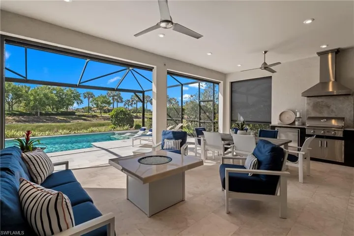 View of patio with grilling area, glass enclosure, an outdoor hangout area, an outdoor kitchen, and an outdoor pool