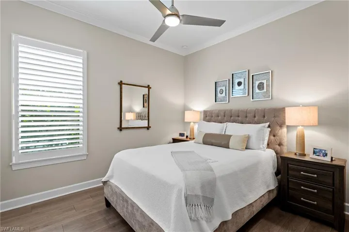Bedroom featuring dark wood-style floors, a ceiling fan, crown molding, and baseboards