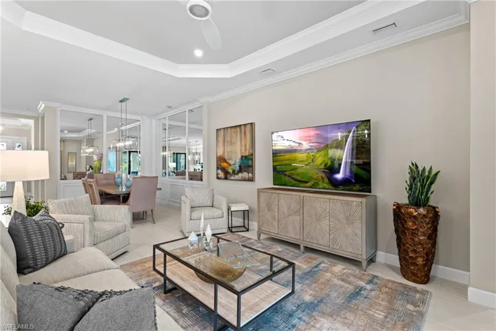 Living room with crown molding, a ceiling fan, visible vents, and a tray ceiling