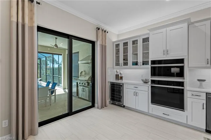 Kitchen with glass insert cabinets, beverage cooler, light countertops, ornamental molding, and decorative backsplash