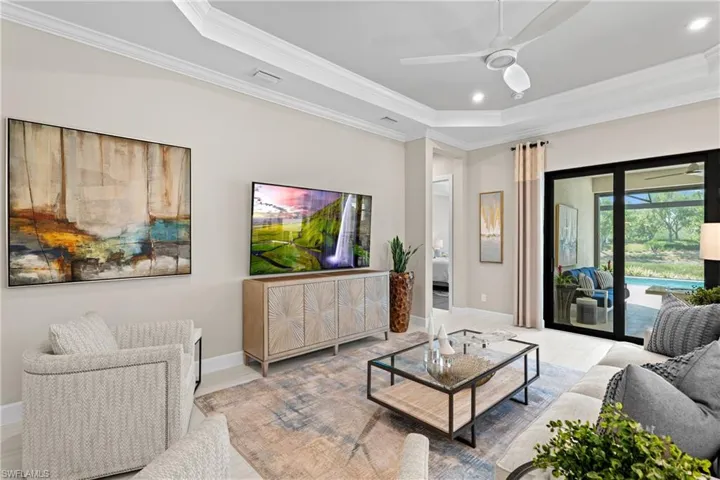 Living area featuring ornamental molding, a ceiling fan, a tray ceiling, recessed lighting, and baseboards