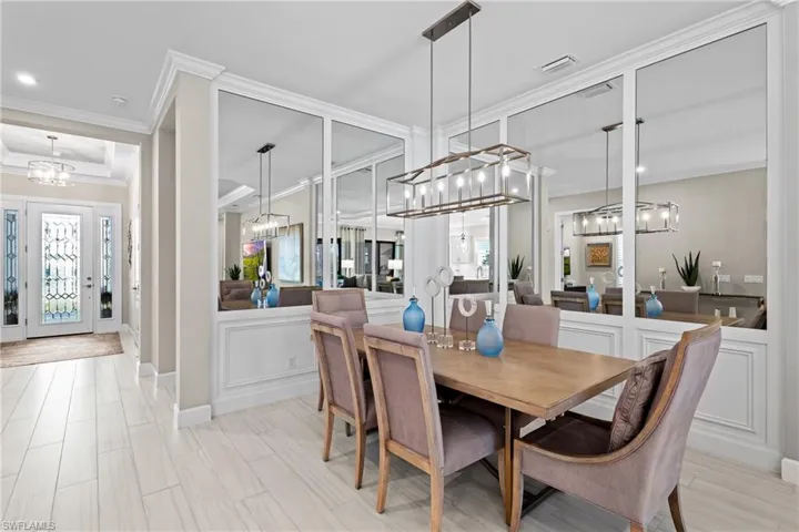 Dining area with crown molding, a decorative wall, visible vents, and a chandelier