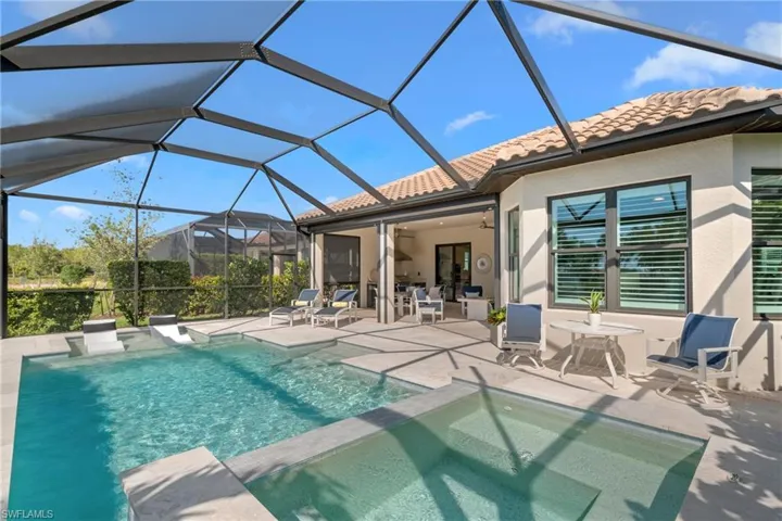 View of swimming pool featuring glass enclosure, a patio, a pool with connected hot tub, and ceiling fan