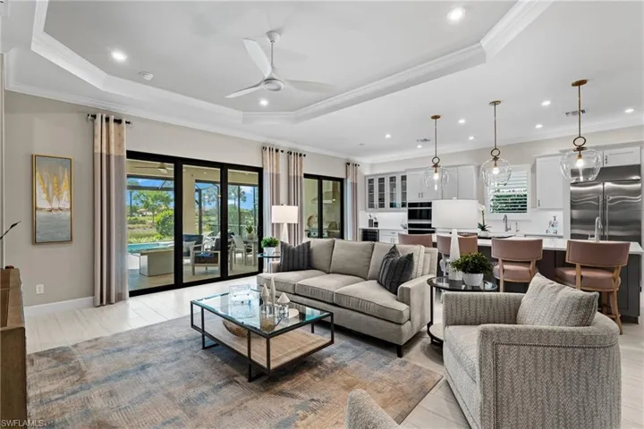 Living room with a ceiling fan, a raised ceiling, a healthy amount of sunlight, and ornamental molding