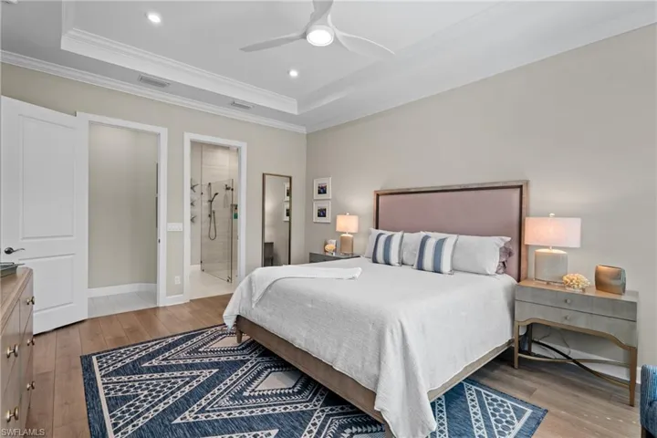 Bedroom with light wood-style flooring, a tray ceiling, and ornamental molding