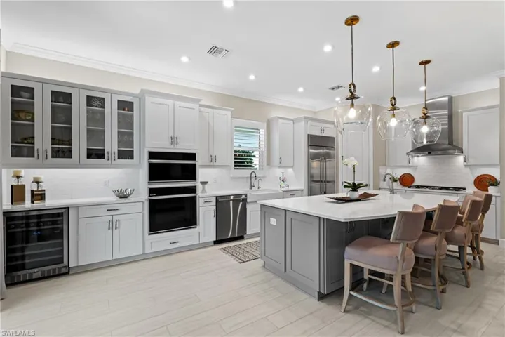 Kitchen featuring visible vents, wine cooler, light countertops, appliances with stainless steel finishes, and wall chimney exhaust hood