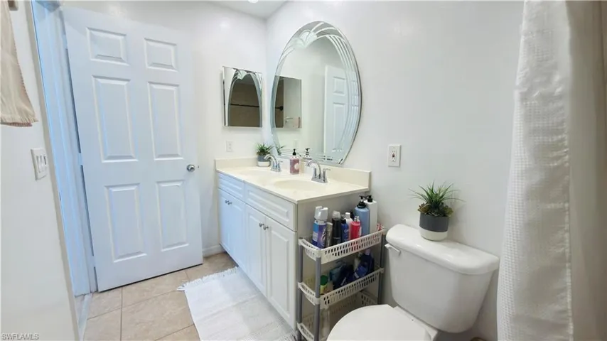 Bathroom with double vanity and light, tile patterned floors