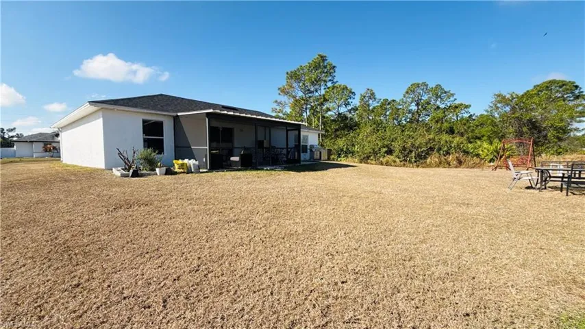 Rear view of house with a sunroom, a lawn, and stucco siding