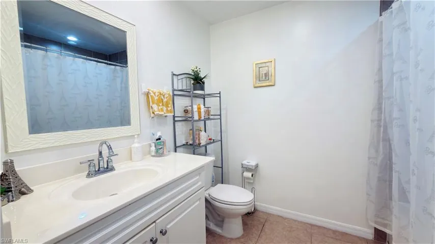 Full bath featuring vanity, curtained shower, and light tile patterned floors