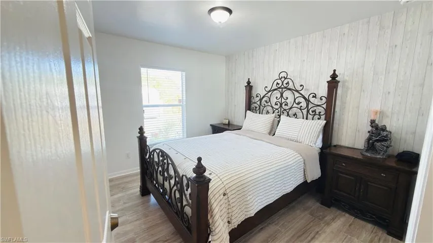 Bedroom with wood finished floors and an accent wall