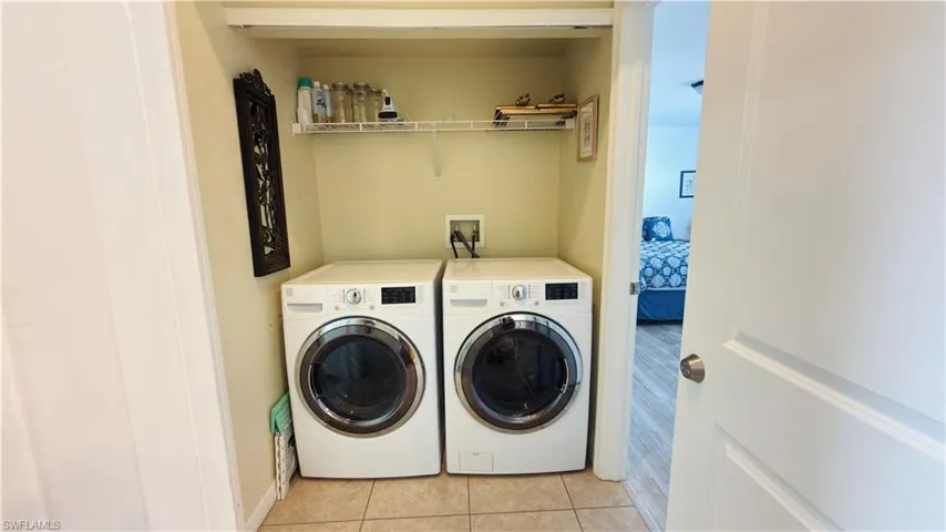 Laundry area with light tile patterned floors and washer and clothes dryer