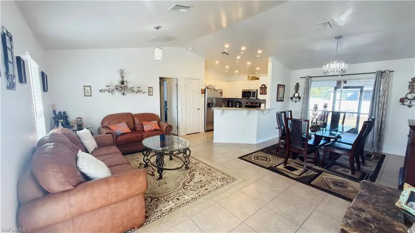 Living area with a high ceiling, light tile patterned flooring, and a chandelier