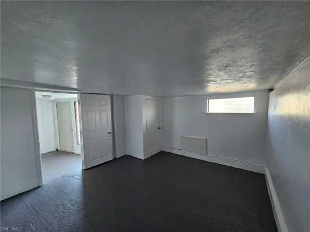Basement with dark carpet and a textured ceiling