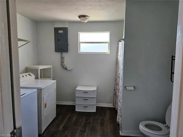 Laundry room with electric panel, dark wood-style flooring, and washer and dryer