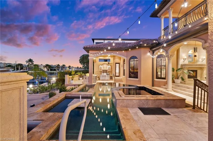 Pool at dusk featuring a patio area and an in ground hot tub