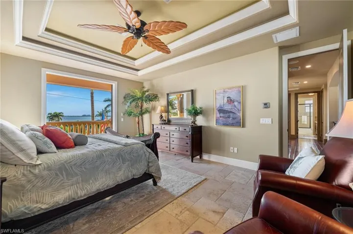 Bedroom featuring a water view, a tray ceiling, ornamental molding, and ceiling fan