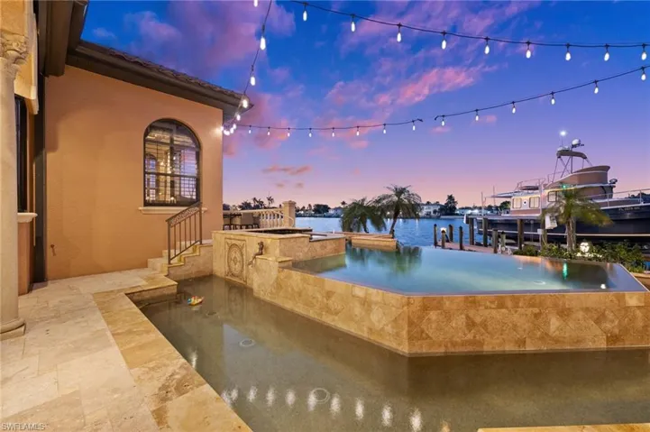 Pool at dusk with an outdoor bar and a water view