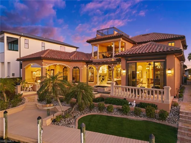 Back house at dusk featuring ceiling fan, a patio, and a balcony