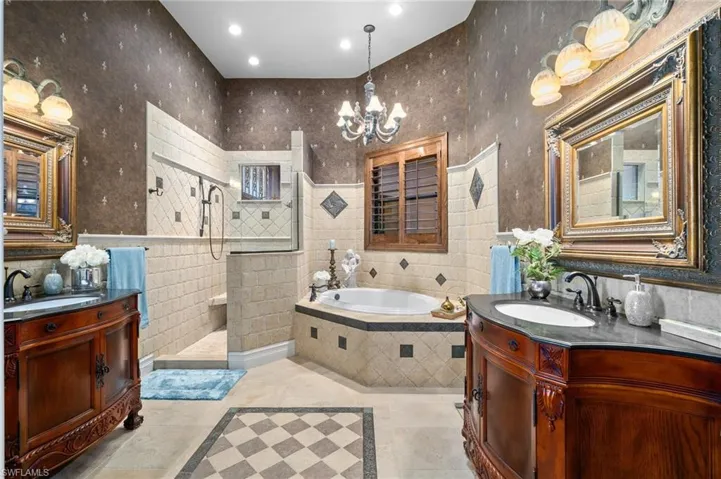 Bathroom featuring tile walls, plus walk in shower, vanity, and a notable chandelier