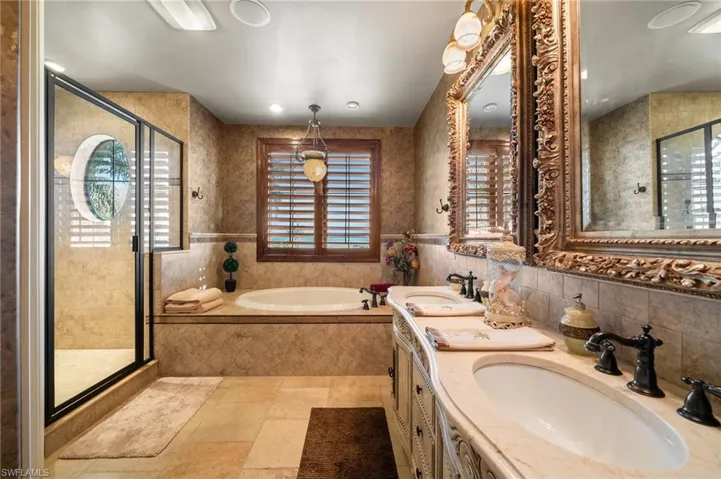 Bathroom with tile walls, independent shower and bath, and vanity