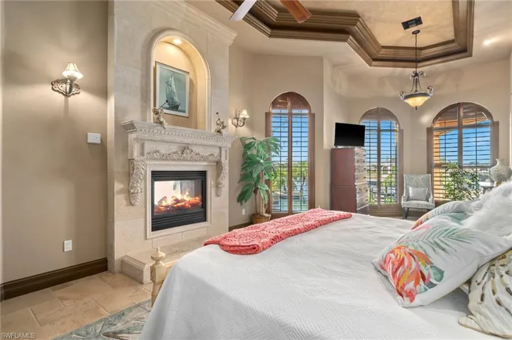Bedroom with a tray ceiling, ornamental molding, and a fireplace