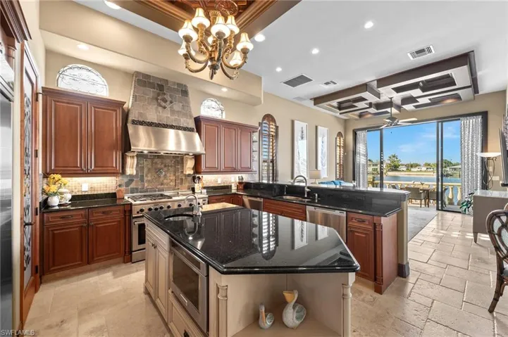 Kitchen featuring dark stone countertops, stainless steel appliances, a kitchen island with sink, and decorative backsplash