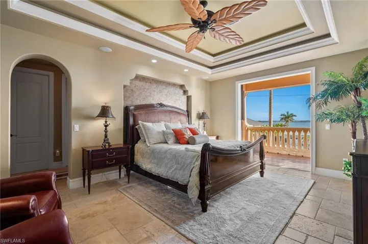 Bedroom with ceiling fan, ornamental molding, a raised ceiling, and access to exterior