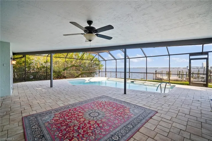 View of pool with a water view, a patio, a lanai, and ceiling fan