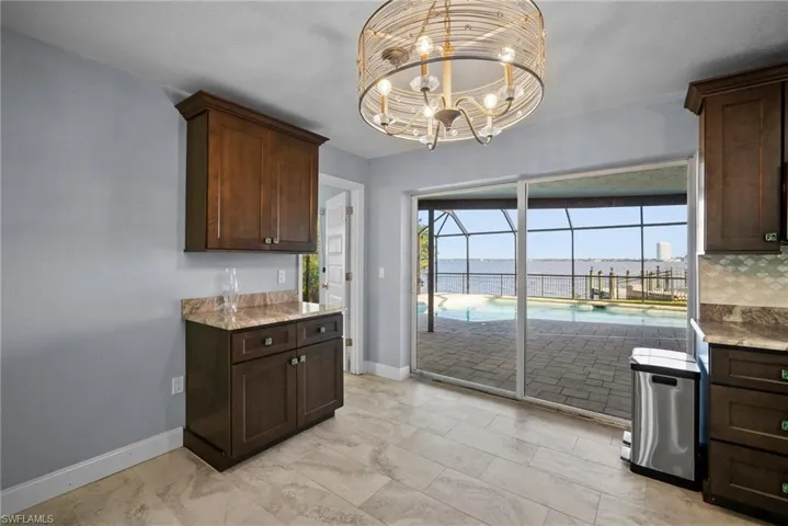 Kitchen featuring light stone countertops, a water view, dark brown cabinets, and a chandelier