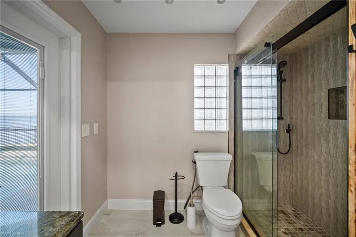 Bathroom with tile patterned floors, a shower with door, and toilet