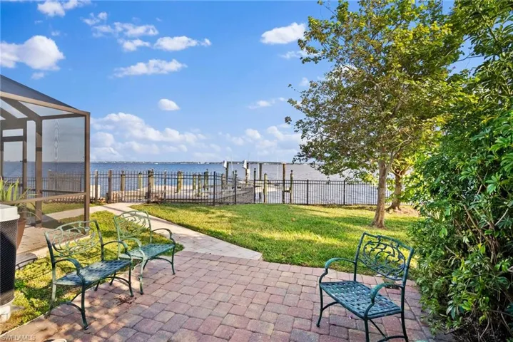 View of patio featuring glass enclosure and a water view