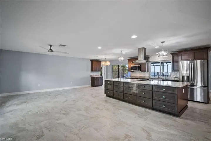 Kitchen with a center island, dark brown cabinets, appliances with stainless steel finishes, pendant lighting, and island exhaust hood