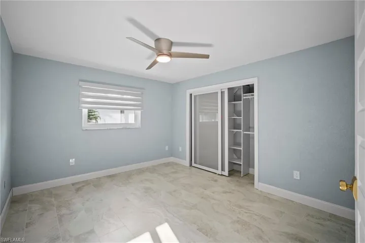 Unfurnished bedroom with ceiling fan and a closet