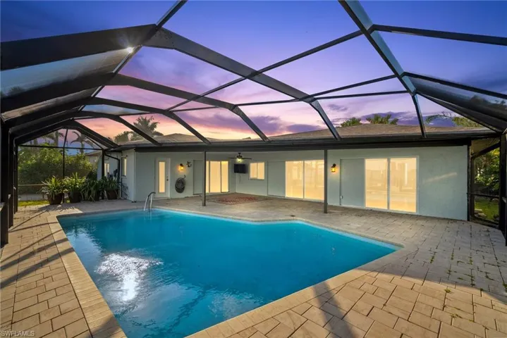 Pool at dusk with a lanai and a patio area