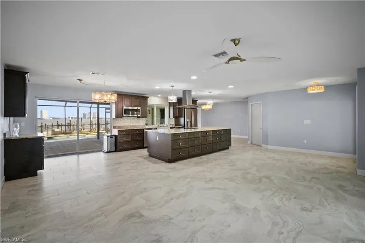 Kitchen with a kitchen island, appliances with stainless steel finishes, island range hood, pendant lighting, and dark brown cabinetry