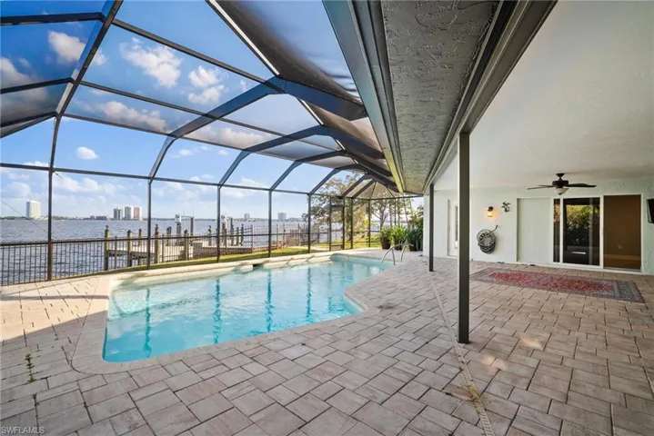 View of pool featuring a patio, ceiling fan, and glass enclosure