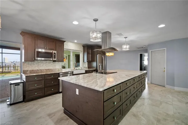 Kitchen featuring sink, appliances with stainless steel finishes, hanging light fixtures, island exhaust hood, and a kitchen island