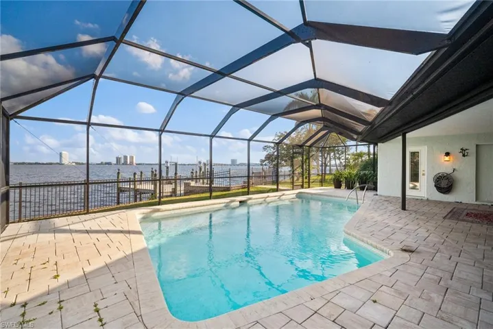 View of swimming pool with a patio, a water view, and a lanai
