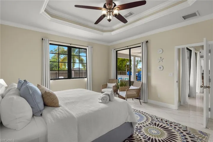 Tiled bedroom featuring crown molding, a raised ceiling, and ceiling fan