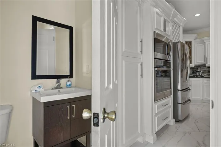 Pool 1/2 bath with crown molding, tile patterned floors, toilet, tasteful backsplash, and vanity