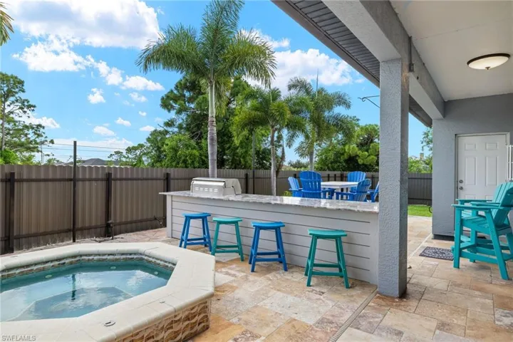 View of swimming pool featuring a bar, a patio area, and an in ground hot tub