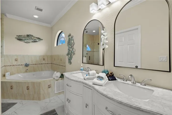 Bathroom featuring ornamental molding, vanity, a relaxing tiled tub, and tile patterned flooring