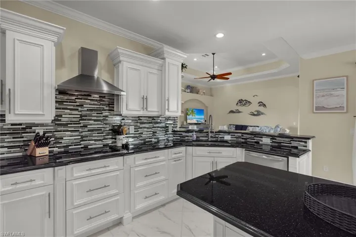 Kitchen with white cabinetry, dishwasher, sink, wall chimney exhaust hood, and light tile patterned flooring