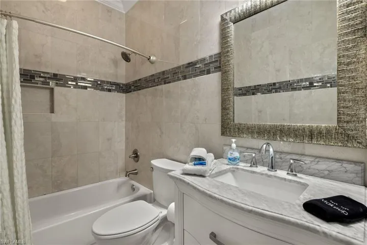 2nd bathroom featuring vanity, tile walls, shower / tub combo, and toilet
