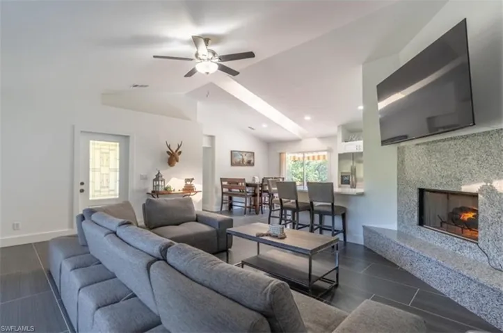 Living room with a high end fireplace, a ceiling fan, and a high ceiling
